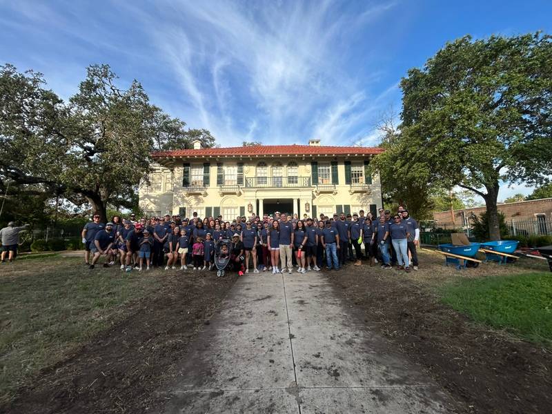 About 100 HOLT volunteers gather for a group photo in front of the Davidson House at Respite Care of San Antonio