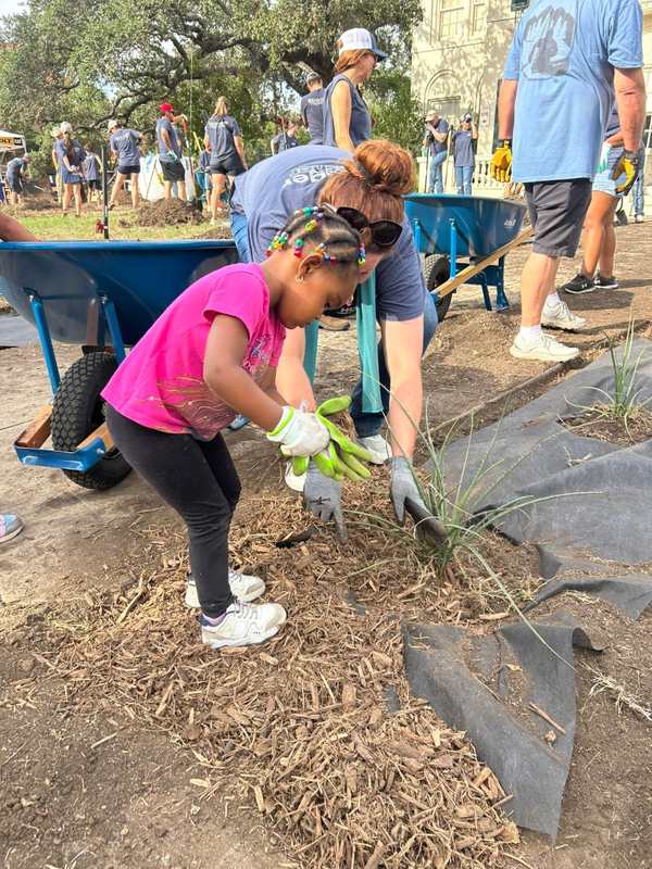 A young volunteer helps plant greenery alongside HOLT team members