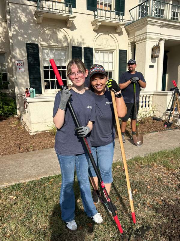 HOLT volunteers pose with rakes and shovels in front of the Respite Care house