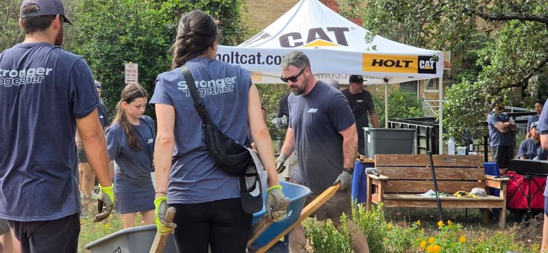 HOLT volunteers haul mulch past the HOLT CAT tent during the landscaping project