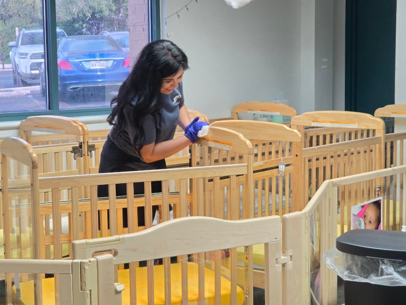 A HOLT volunteer sanitizes cribs in a Respite Care childcare classroom