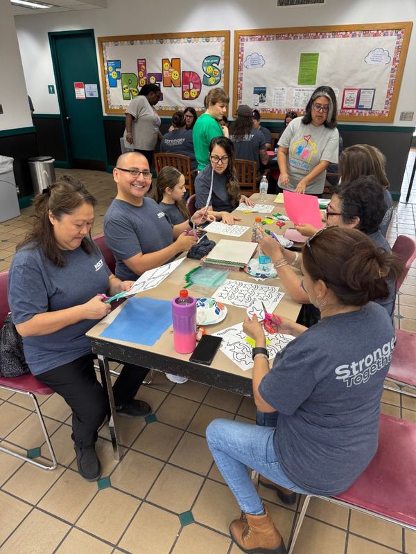 Volunteers work around a crafts table inside a Respite Care classroom
