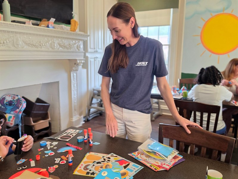 A smiling HOLT volunteer helps prepare colorful craft kits for the children
